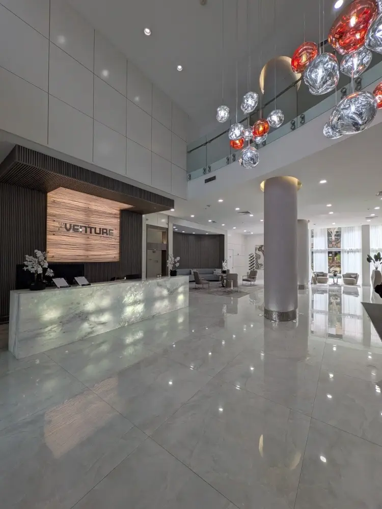 Double-height East tower lobby at The Venture with marble floors and copper and chrome pendant lights